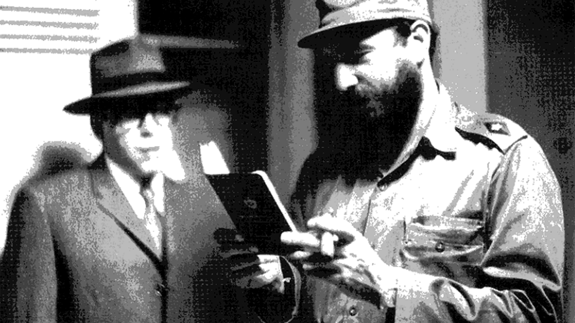 Foto tomada a fines de marzo de 1965 en una casa de seguridad de La Habana. Fidel Castro observa el pasaporte falso del Che, caracterizado como el comerciante uruguayo Ramón Benítez antes de viajar a Bolivia