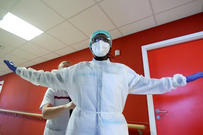 FILE PHOTO: A member of medical personnel gets dressed in a protective suit as patients suffering from coronavirus disease (COVID-19) are treated at CHIREC St Anne-St Remi Clinic in Brussels, Belgium, October 6, 2020. REUTERS/Yves Herman/File Photo