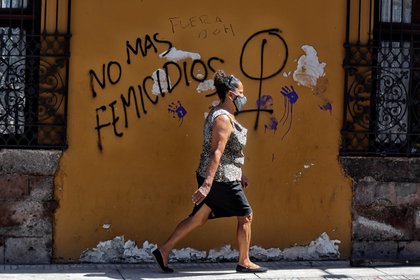 Una mujer camina frente a un mural que reclama que no haya más femicidios (EFE/Gustavo Amador)