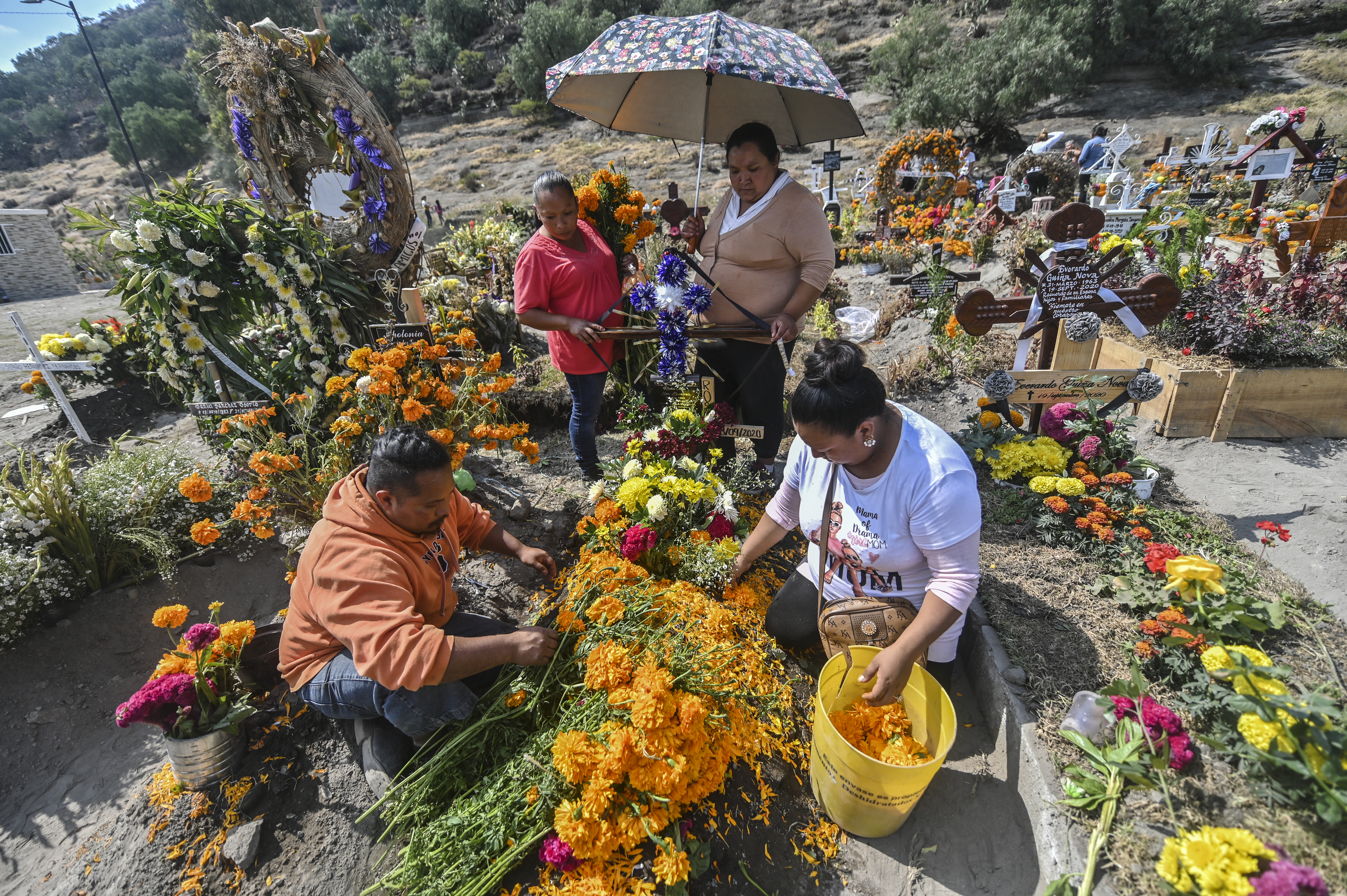 Personas decoran la tumba de un familiar antes del Día de Muertos en el Panteón Municipal en Valle de Chalco, Estado de México, México, el 28 de octubre de 2020, en medio de la pandemia del coronavirus COVID-19.