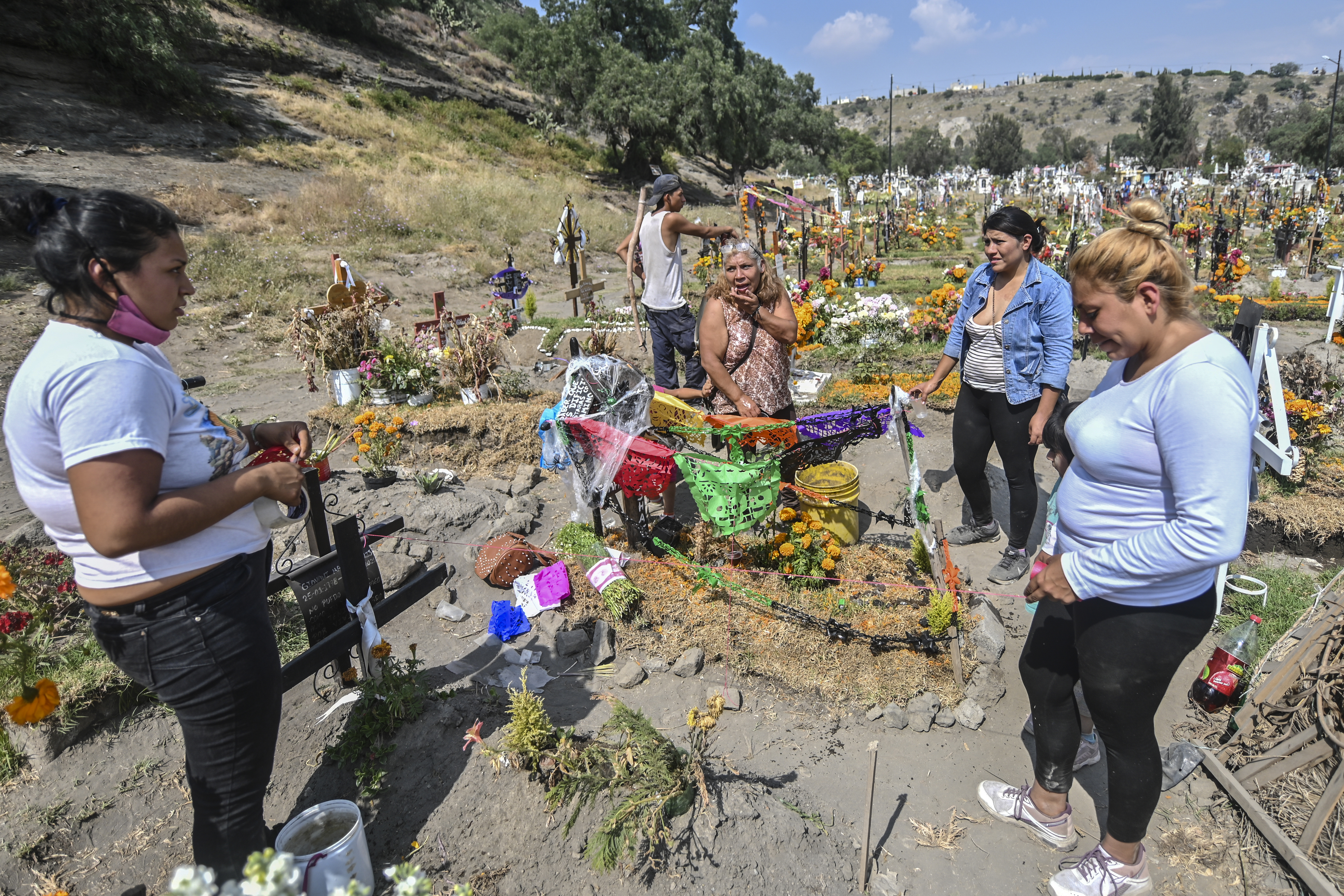 Personas decoran la tumba de un familiar víctima del COVID-19, antes del Día de Muertos en el Panteón Municipal en Valle de Chalco, Estado de México, México, el 28 de octubre de 2020, en medio de la pandemia del coronavirus COVID-19. 