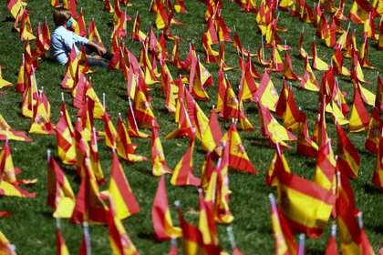 ARCHIVO FOTOGRÁFICO: Una persona sentada junto a las banderas españolas colocadas en memoria de las víctimas del COVID-19 en un parque de Madrid, España, el 27 de septiembre de 2020. (REUTERS/Sergio Pérez)