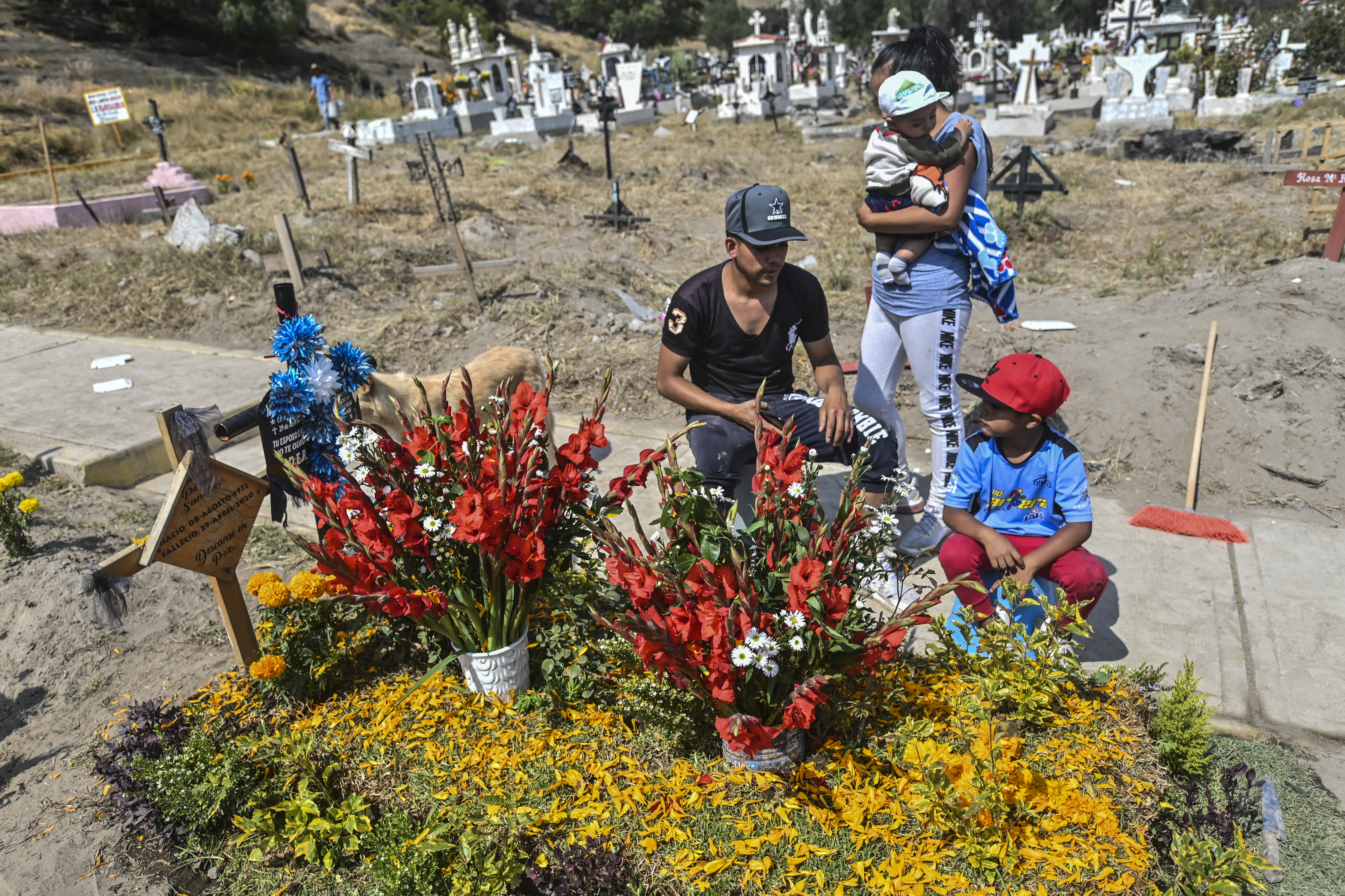 Personas decoran la tumba de un familiar víctima del COVID-19, antes del Día de Muertos en el Panteón Municipal en Valle de Chalco, Estado de México, México, el 28 de octubre de 2020, en medio de la pandemia del coronavirus COVID-19. 