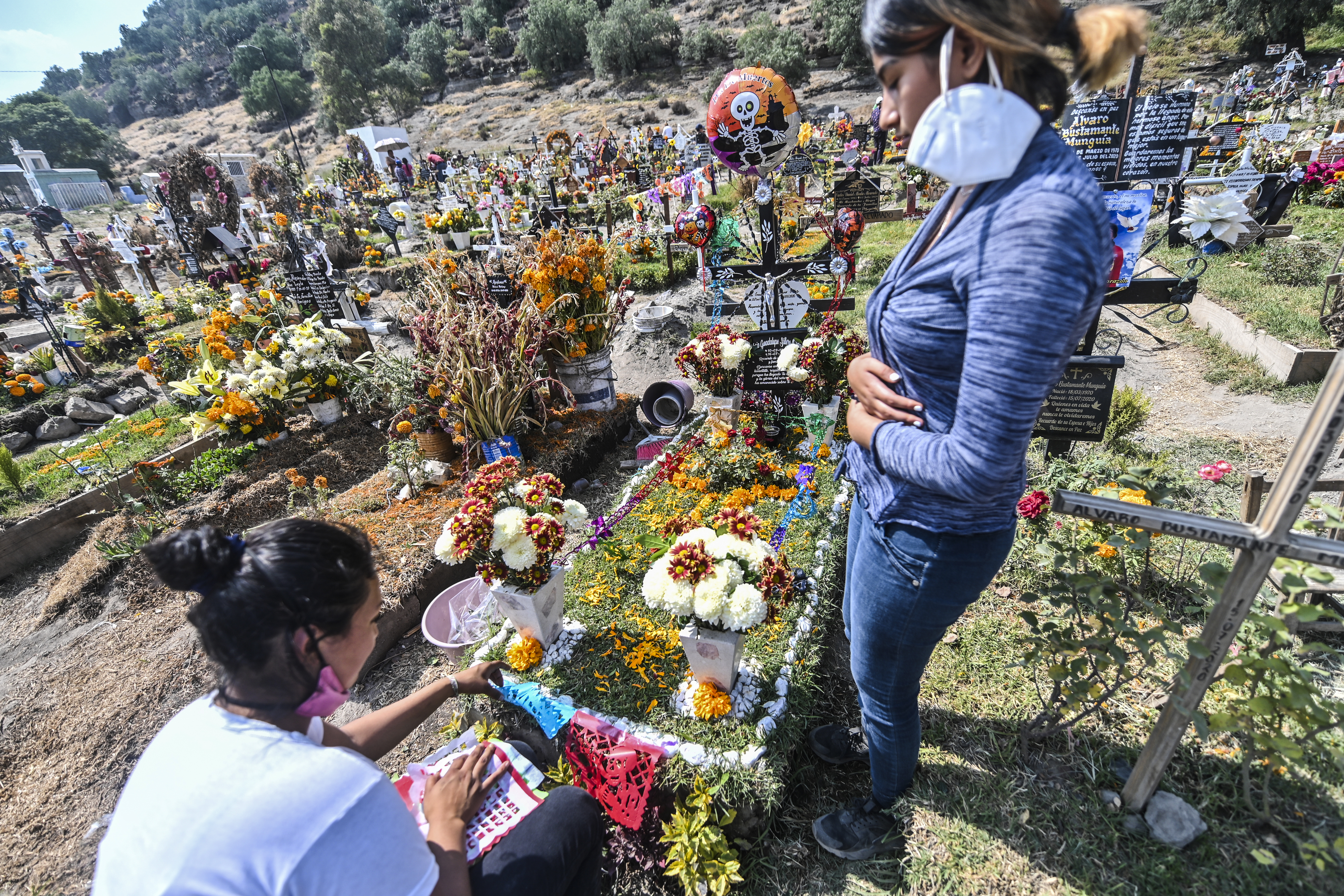 Personas decoran la tumba de un familiar víctima del COVID-19, antes del Día de Muertos en el Panteón Municipal en Valle de Chalco, Estado de México, México, el 28 de octubre de 2020, en medio de la pandemia del coronavirus COVID-19. 