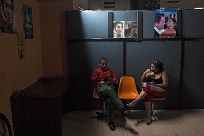 Dos personas conversan mientras comen en el sótano donde viven (Cristian Hernandez / AFP)