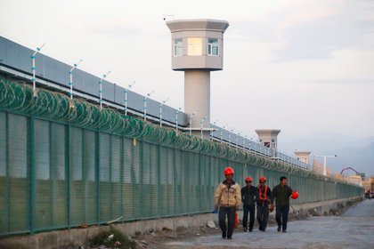Trabajadores caminan junto a la valla perimetral de lo que se conoce oficialmente como centro de formación profesional en Dabancheng, en la Región Autónoma Uigur de Xinjiang (REUTERS/Thomas Peter)