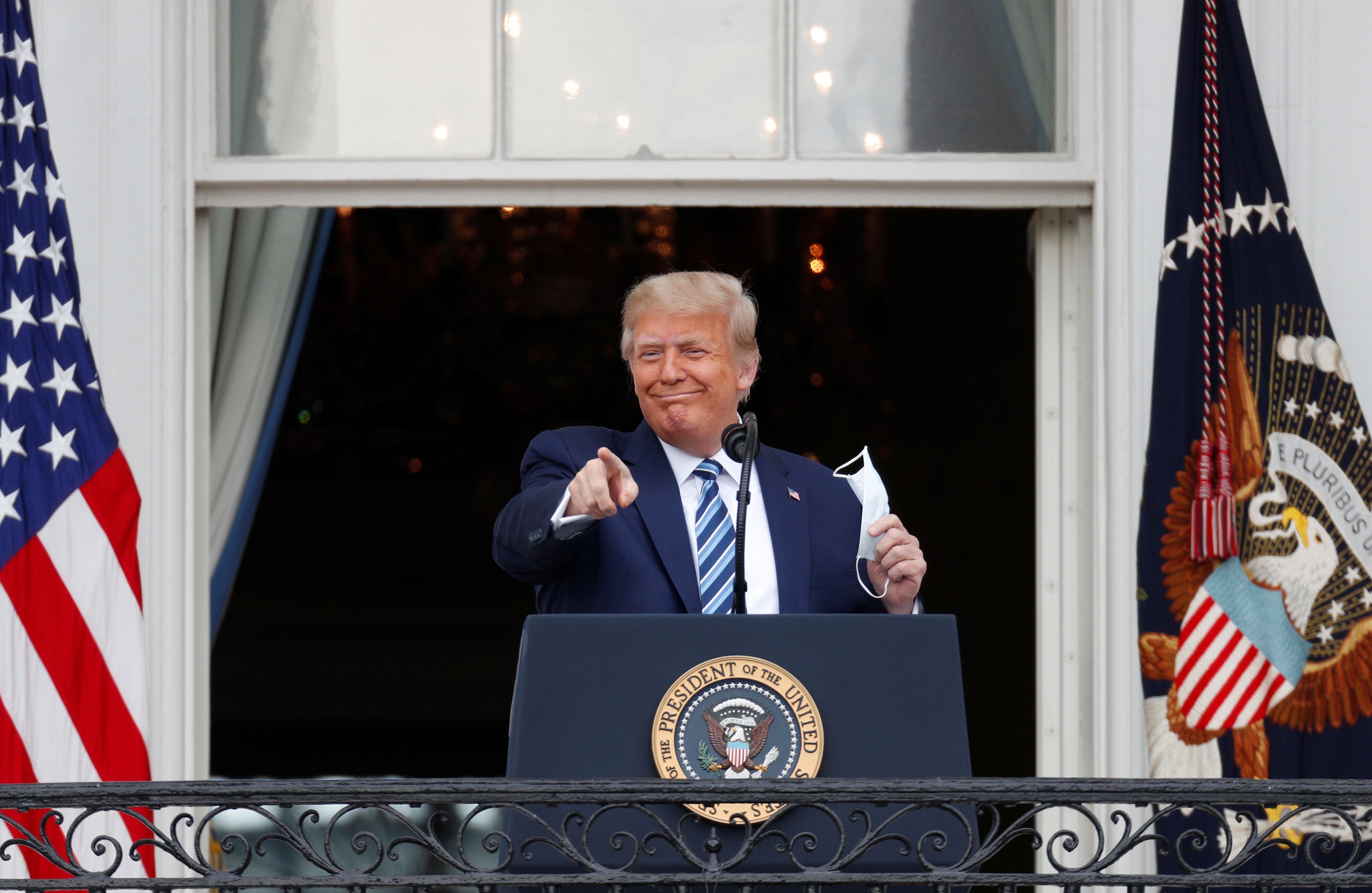 U.S. President Donald Trump gestures as he stands on a White House balcony speaking to supporters gathered on the South Lawn for a campaign rally that the White House is calling a 