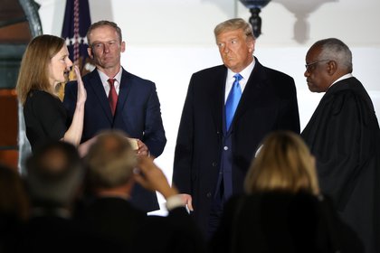 La jueza Amy Coney Barrett es juramentada como juez de la Corte Suprema de los Estados Unidos por el juez de la Corte Suprema Clarence Thomas mientras su esposo Jesse Barrett y el presidente Donald Trump miran.   REUTERS/Jonathan Ernst