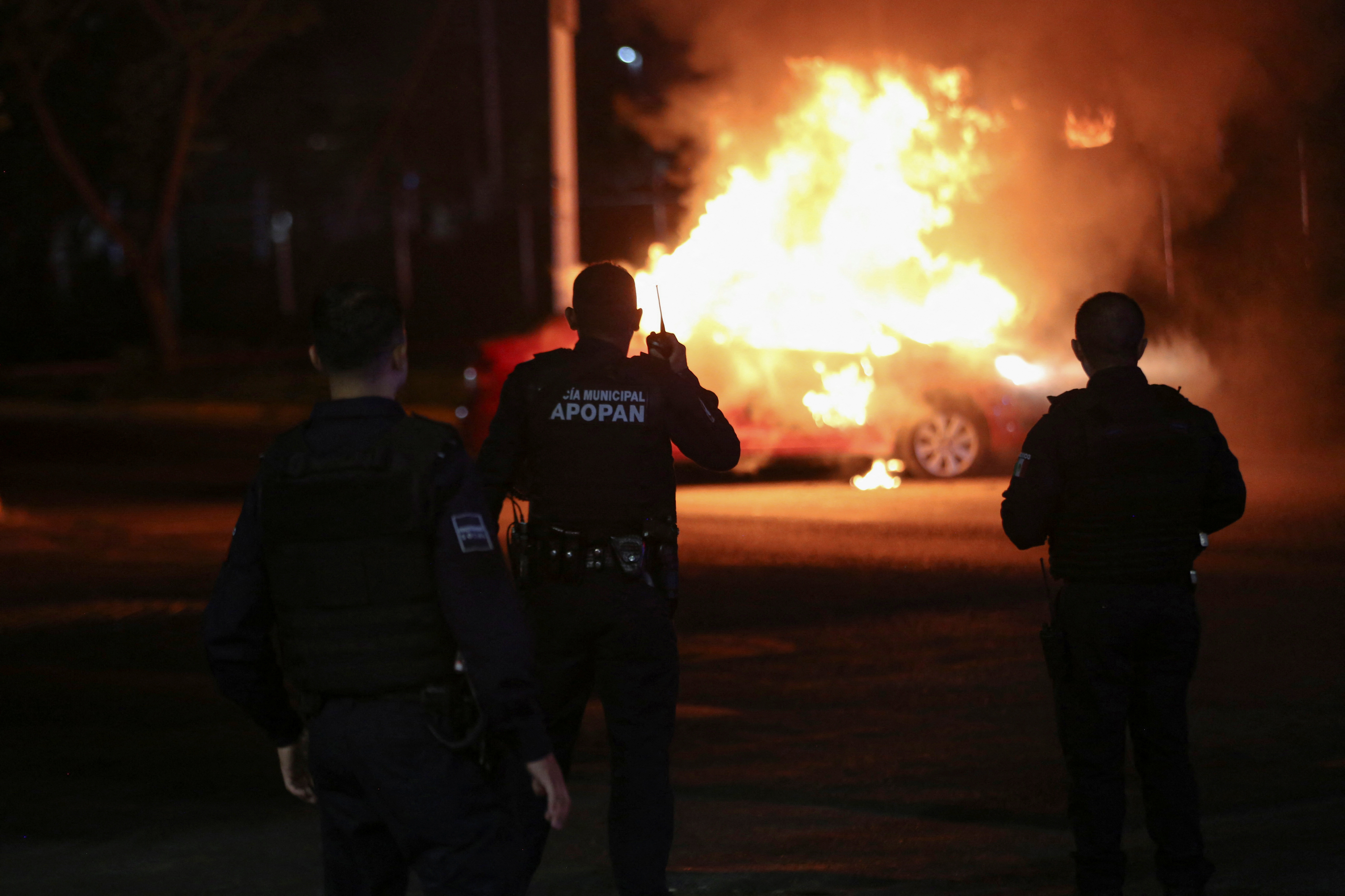 Agentes de policía se paran en una escena donde miembros del Cártel Jalisco Nueva Generación incendiaron un vehículo luego de la detención de uno de sus líderes por el Ejército, en Zapopan (Foto: Reuters)